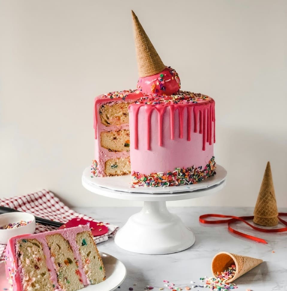 A cake with pink icing and sprinkles on top of it.