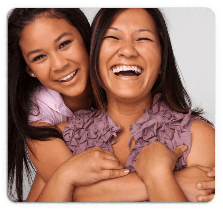 Two women smiling for the camera and laughing.